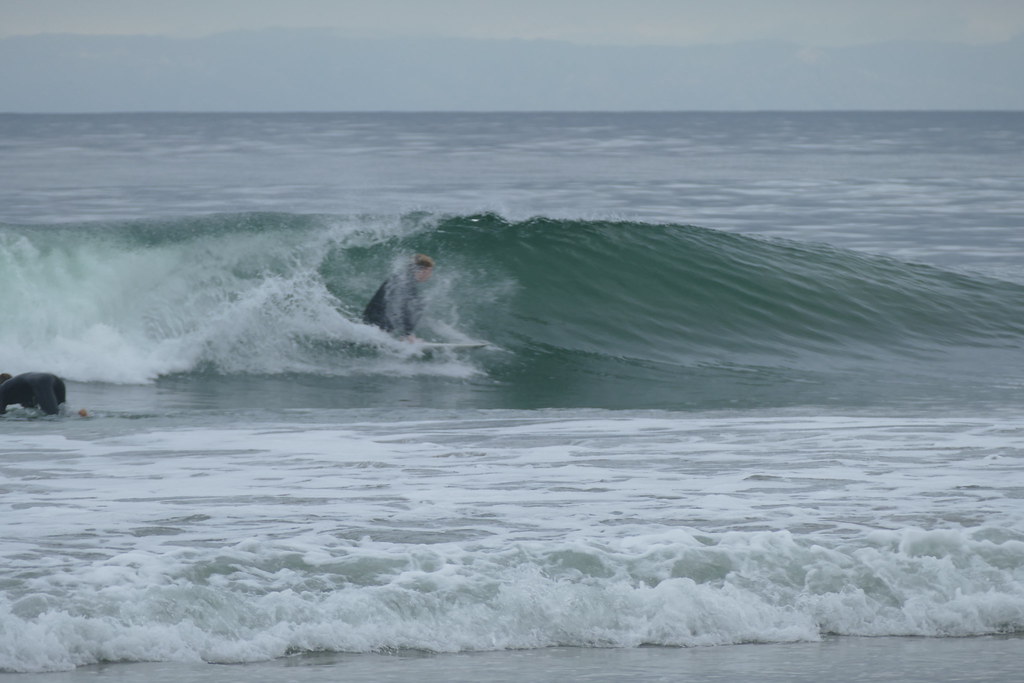 CdM surfer crouched low under the lip of a breaking wave